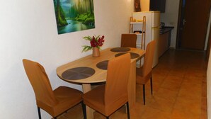 A small dining area with a table and chairs, a painting on the wall, and a refrigerator in the background. - Apartman Slavica by Interhome (Karin)