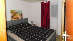 A bedroom with a bed, a painting on the wall, a lamp, and a window with curtains. - Apartman Slavica by Interhome (Karin)