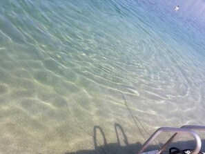 A clear view of a sandy beach with shallow water, a metal ladder, and a distant buoy. - Sunara mit Terrasse und Kinderpool by Interhome (Podorljak)
