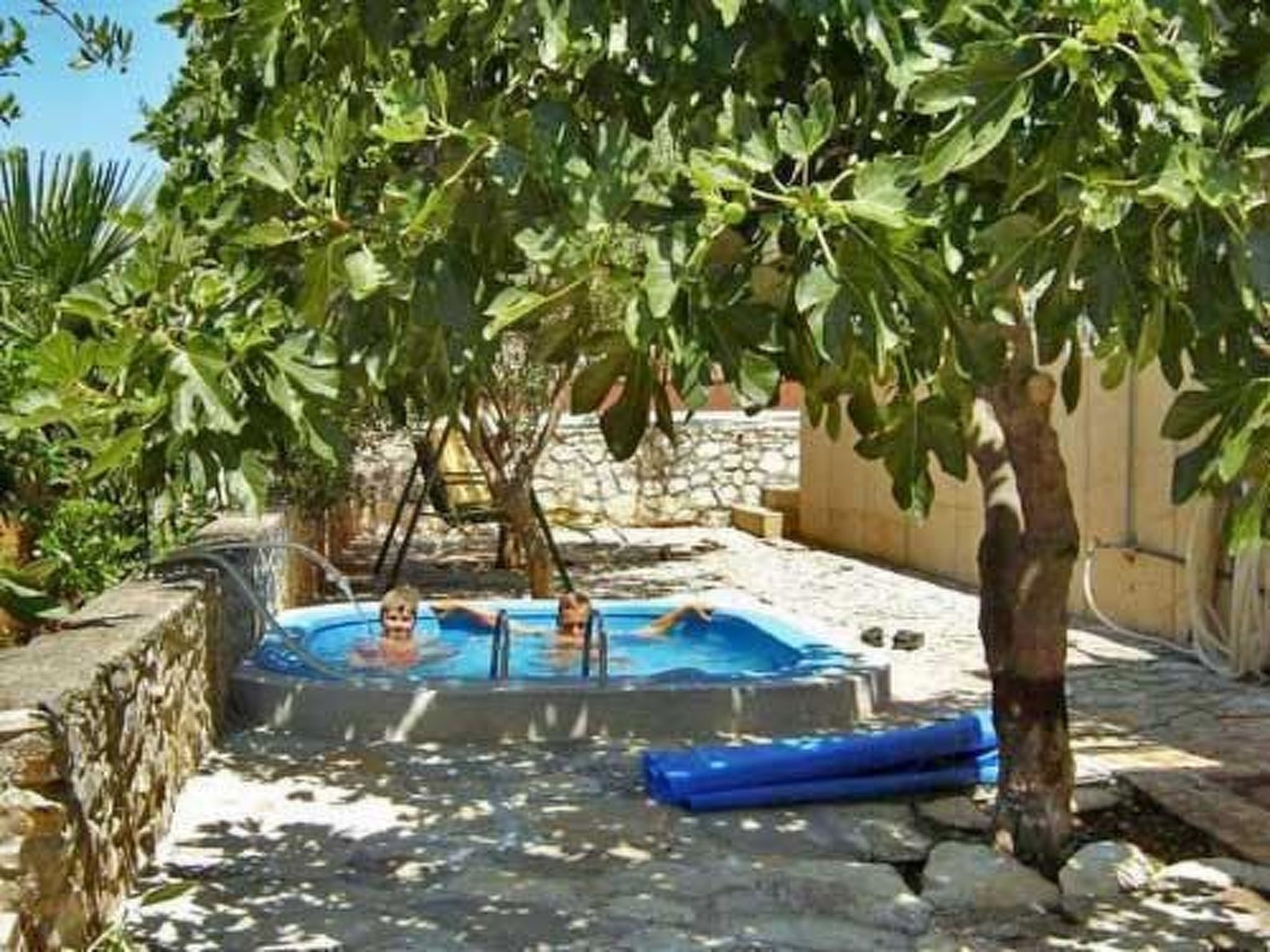 A swimming pool surrounded by stone walls and lush greenery.