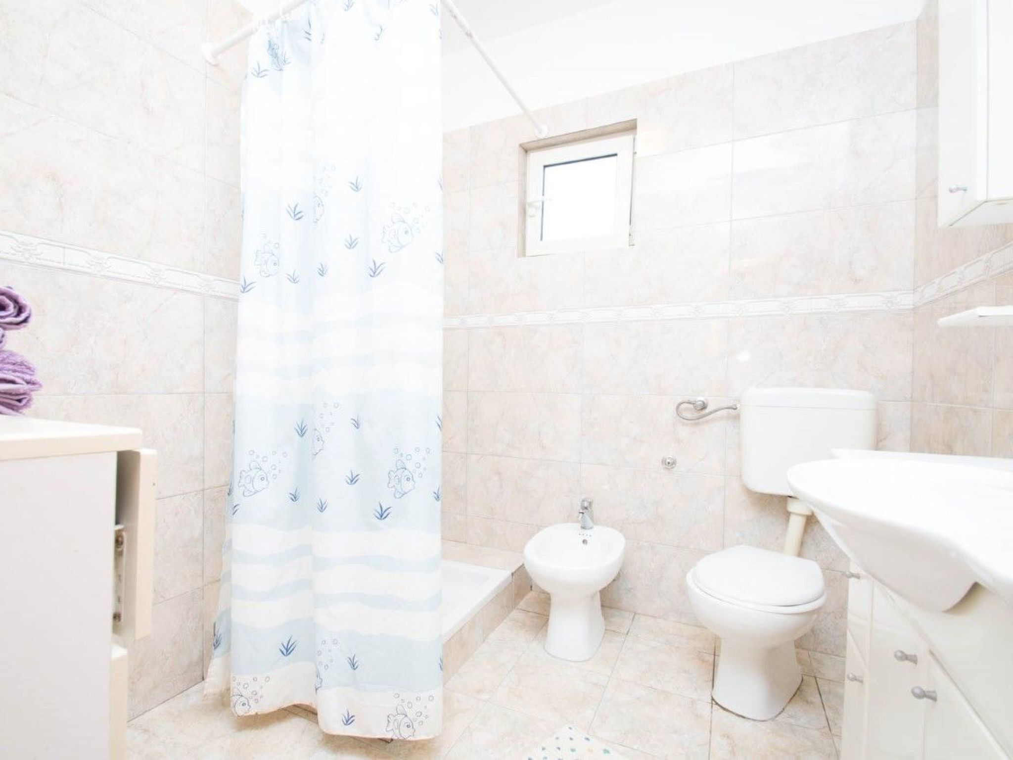Une salle de bain équipée d’un rideau de douche, d’un bidet, de toilettes et d’un lavabo.