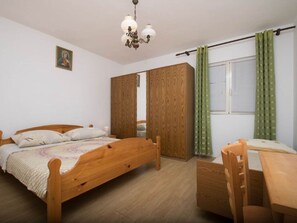 A bedroom with a wooden bed, a wooden desk, a chair, a wardrobe, a mirror, and a ceiling light fixture. - Wohnung Delfin mit großer Terrasse - TA Leut Agency by Interhome (Privlaka)