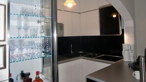 Eine moderne Küche mit Weinkühlschrank mit Glastür, einer Kaffeemaschine und einem Edelstahl-Wasserkocher.