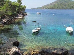 Eine Küstenlandschaft mit klarem türkisblauem Wasser, felsigen Ufern und ankernden Booten.