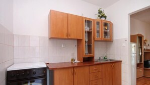Eine Küche mit Holzschränken, einer Edelstahl-Spüle und einem Einbauofen.
