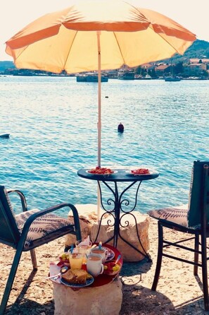 A table with a table umbrella, two chairs, and a tray with food and drinks. - Steinhaus in Strandnähe mit Whirlpool by Interhome (Ugljan/Preko)