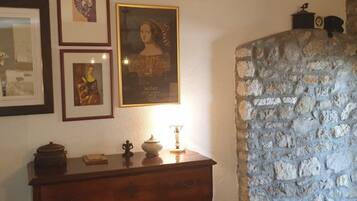A room with a stone wall, a wooden dresser, and three framed pictures on the wall.