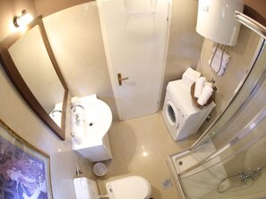Et badeværelse med vask, toilet, vaskemaskine og bruser.
