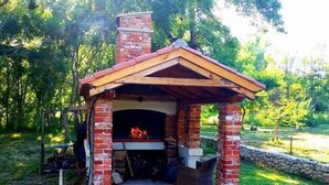 A brick-built outdoor fireplace with a wooden roof and a stone wall foundation. - Am Fluss gelegenes Haus mit Galerieschlafplätzen by Interhome (Nin)