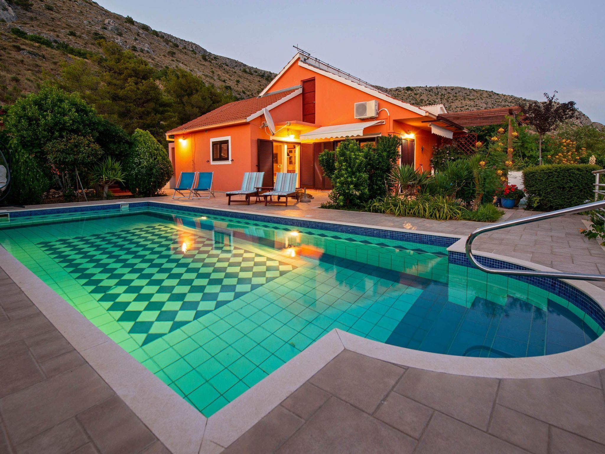 A swimming pool with a checkered pattern, surrounded by a patio area with lounge chairs.