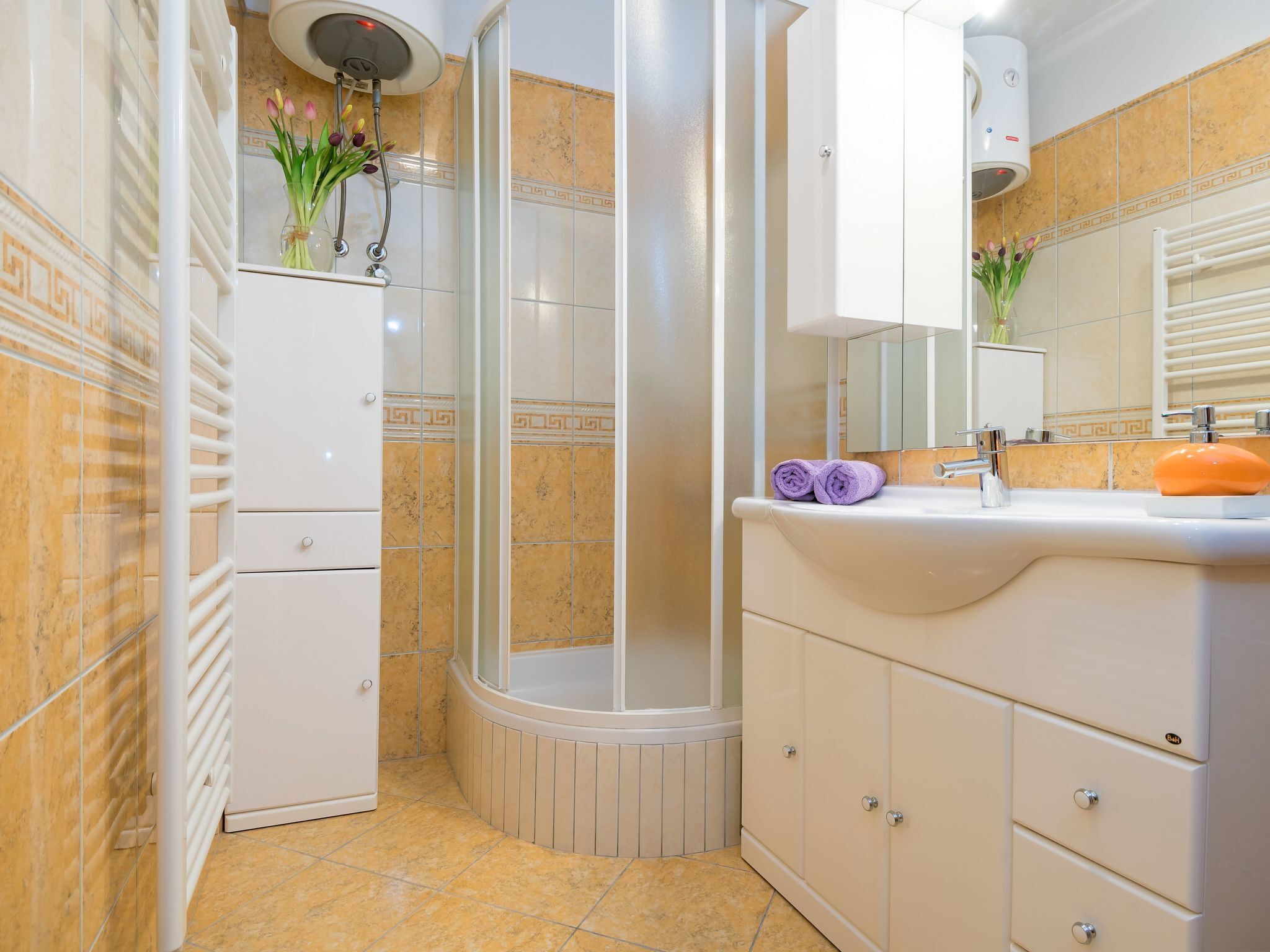 A bathroom with a shower, a vanity with a sink, and a cabinet.