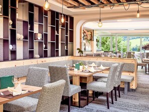 Een restaurant met een lange toonbank, gestreept beklede stoelen en uitzicht op groen buiten.