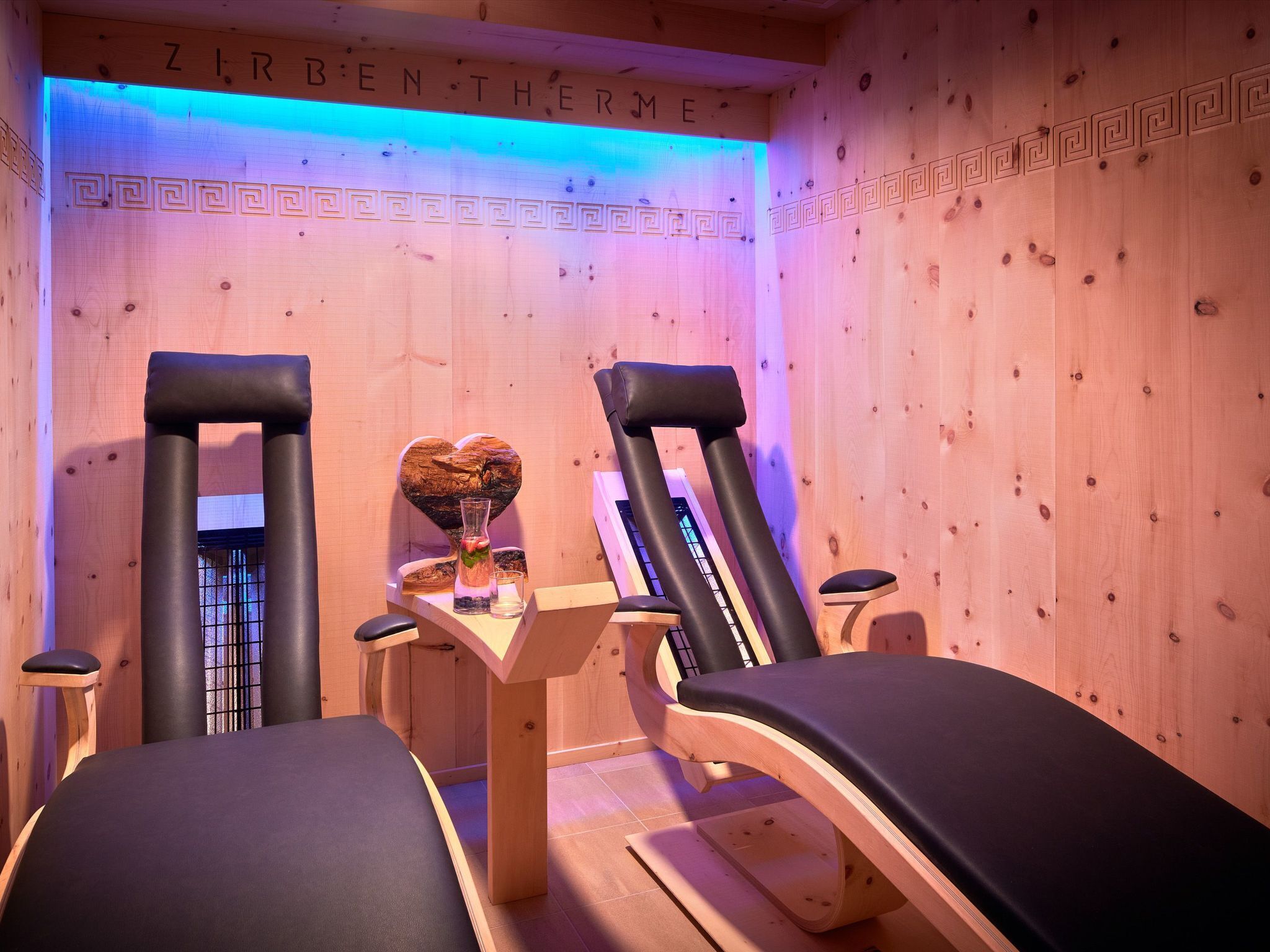 A room with wooden walls and a massage table. There is a heart-shaped wooden sculpture on the table.