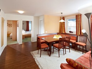 A compact hotel room with a dining area, a sofa, and a window with curtains. - Eck-Haus Nr. 900 by Interhome (Neukirchen am Großvenediger)