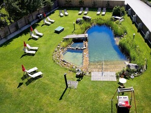 A backyard with a small pond, several lounge chairs, a swing set, and a patio table. - Eck-Haus Nr. 900 by Interhome (Neukirchen am Großvenediger)