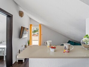 Eine moderne Küche mit einer großen Kochinsel, Blick ins Freie und einem Essbereich mit Tisch und Stühlen.