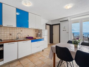 Eine moderne Küche mit weißen Schränken, einem blauen Akzent und einem Essbereich mit Tisch und Stühlen.