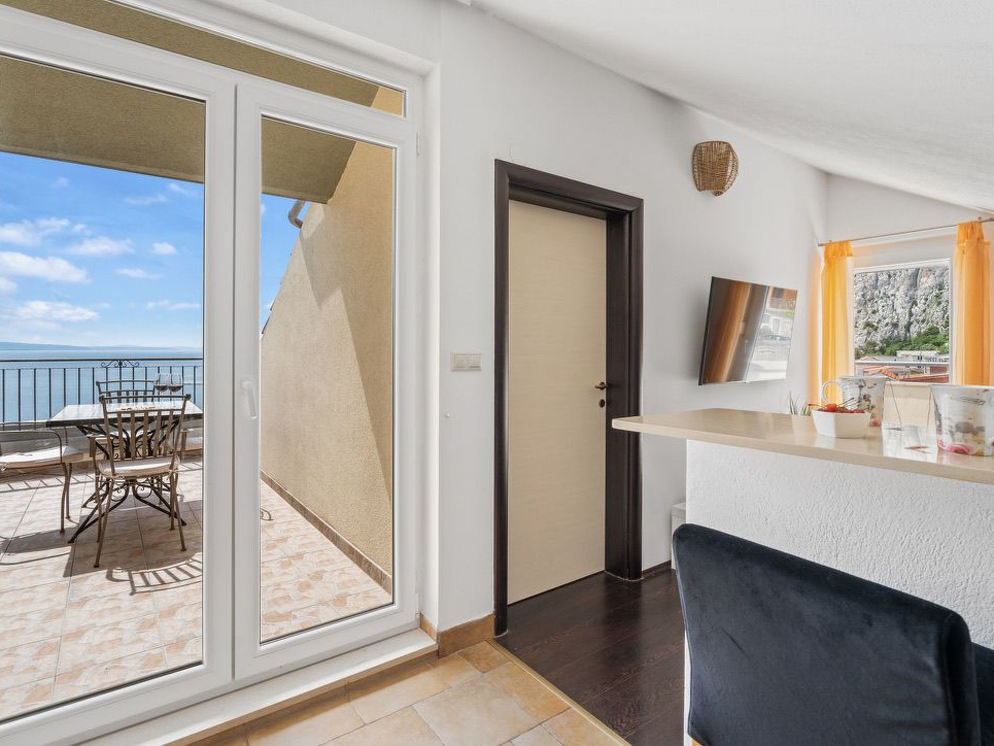 Una habitación con puerta corrediza de vidrio que da a una zona de estar exterior con mesa y sillas.