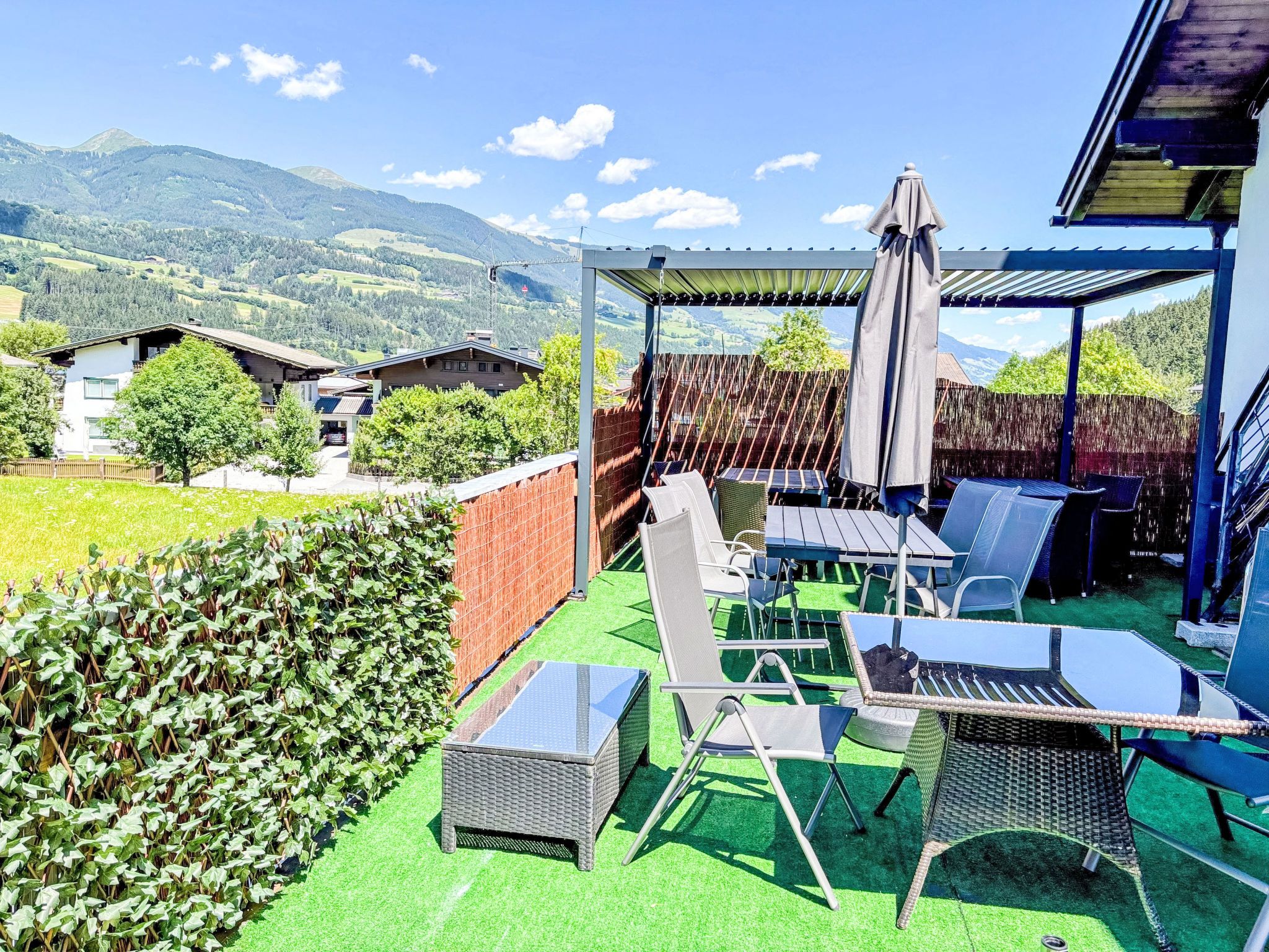 Une terrasse extérieure dotée d’une pergola, de sièges et offrant une vue sur les montagnes.