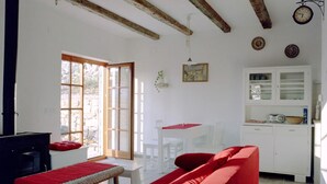Habitació amb un sofà vermell, una taula petita, un armari blanc i un sostre de fusta.