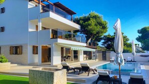 Ein modernes, zweistöckiges Haus mit Pool, Außenbereich und überdachter Terrasse.