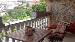 En balkon med et træbord og stole, en fletkurv og en potteplante.