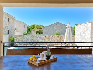 A balcony with a table set for breakfast, overlooking a pool and stone buildings. - Villa Vid 03 mit beheiztem Pool -TA Leut Agency by Interhome (Privlaka)