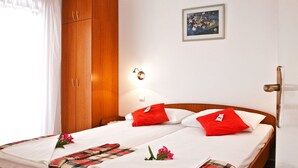 Ein ordentlich bezogenes Bett mit roten Kissen, einer karierten Decke und einer Blumenkomposition.