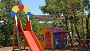 Ein Spielplatz mit Rutsche, Klettergerüst und einem kleinen Spielhäuschen.