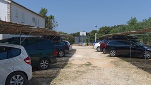 Un parcheggio con diverse auto parcheggiate, un edificio con tetto in tegole e un campo da basket sullo sfondo.