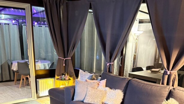 A modern living room with a sectional sofa, a wooden coffee table, and a dining area visible through a glass door. - Wellness-Ferienhaus für 5 Personen by Interhome (Stavenisse)