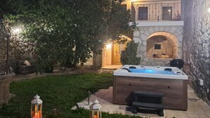 Ein Steinhaus mit Whirlpool, einem steinernen Bogen und einem gut beleuchteten Eingang.