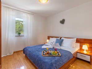 A neatly made bed with a blue blanket, a tray of breakfast items, and a heart-shaped decoration on the wall. - Wohnung mit Terrasse und Meerblick by Interhome (Crikvenica/Dramalj)