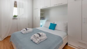 A modern bedroom with a bed, white wardrobe, and a window with sheer curtains. - Wohnung mit schöner Terrasse by Interhome (Crikvenica/Dramalj)