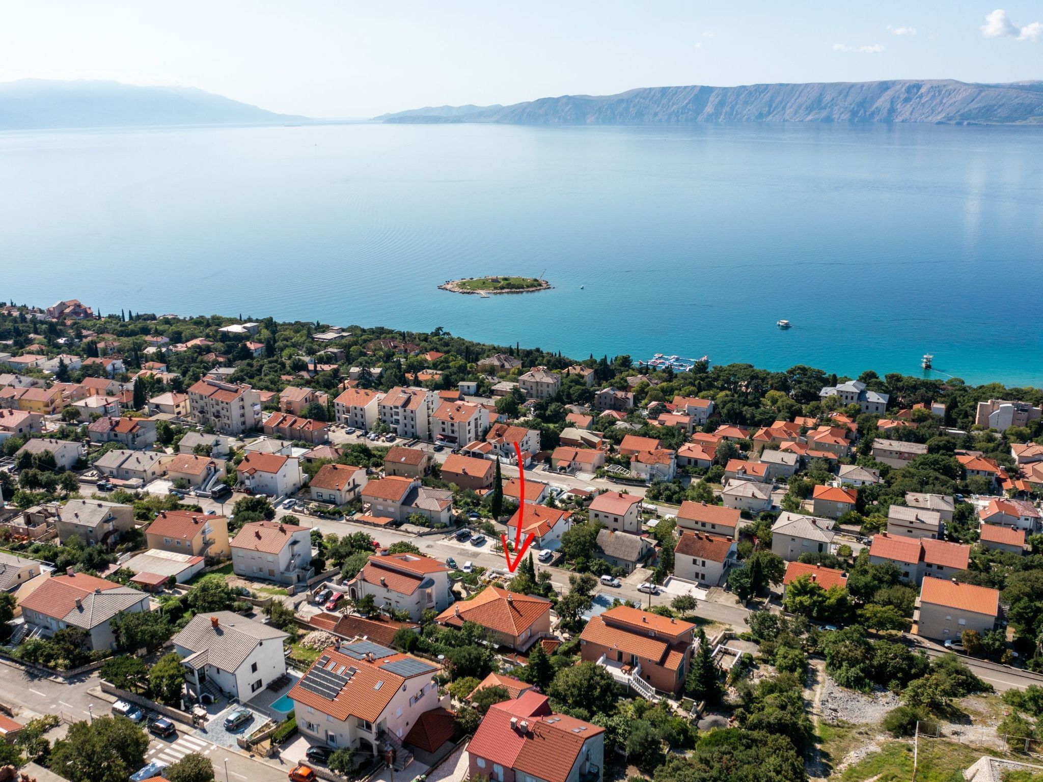 Une vue aérienne d’une ville côtière, avec un port de plaisance, des immeubles d’habitation denses et une vue dégagée sur la mer.