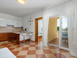 Une cuisine moderne avec un carrelage à motifs, des placards blancs et une horloge au mur.