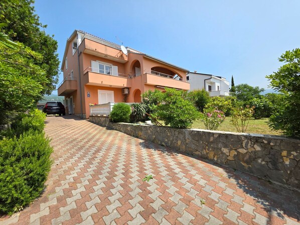 Una casa de dos pisos con un muro de piedra y un camino de entrada pavimentado.