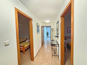 Un pasillo con una cama, un espejo y una mesita.