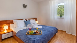 Una habitación de hotel con cama, una bandeja de desayuno, una mesita de noche y una ventana con cortinas.