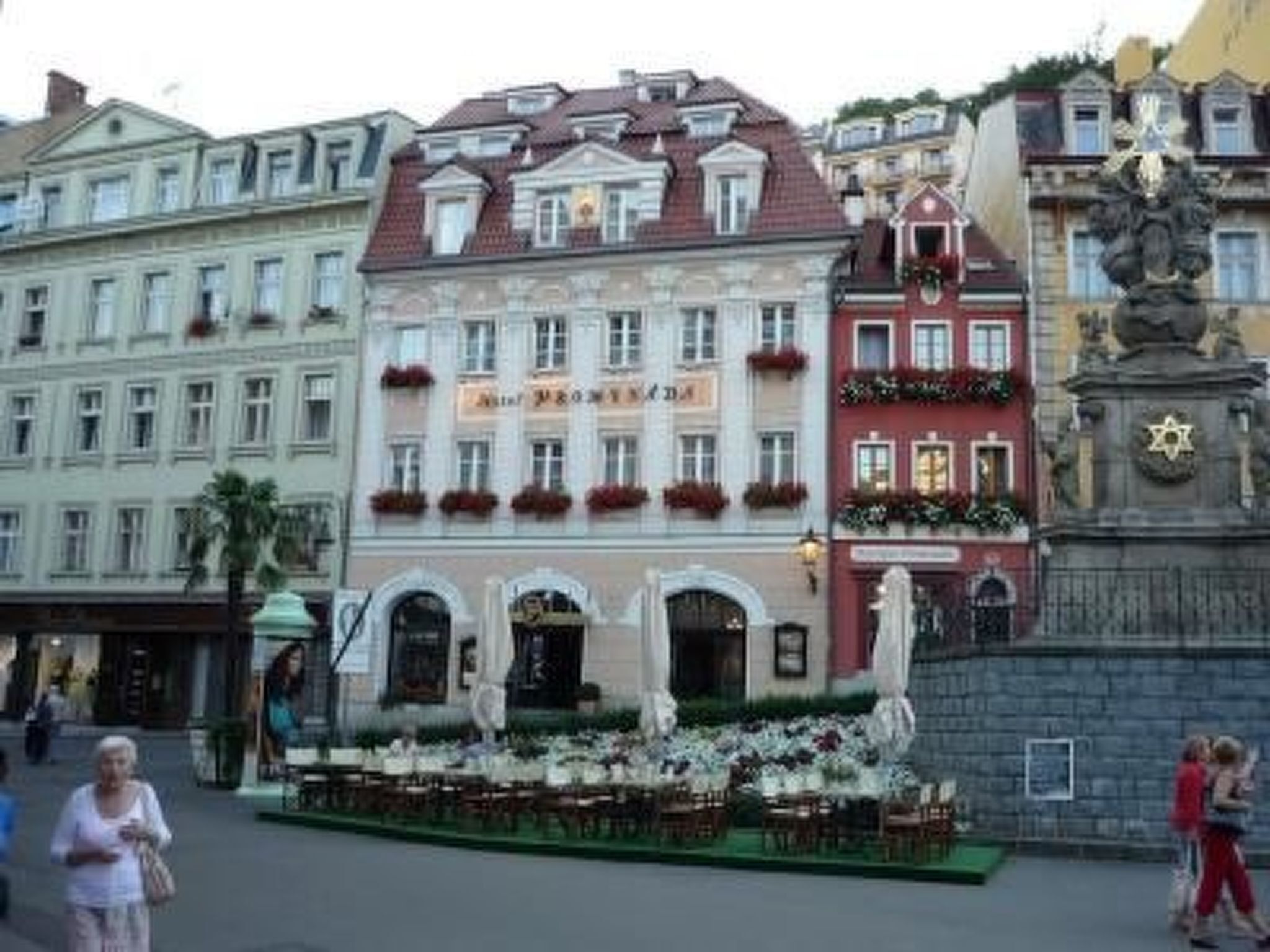 En historisk byggnad med en klassisk europeisk arkitektur, som kännetecknas av en central entré med en dekorativ portal, flera fönster och en balkong med röda blomlådor.