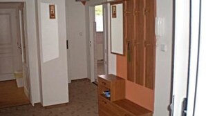 Un pasillo con un armario de madera, un espejo y una puerta.
