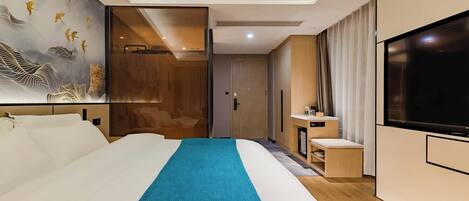 A modern hotel room with a large bed, a TV, a bathroom, and a painting on the wall.