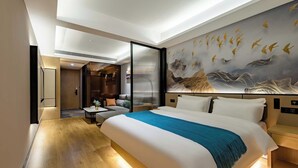 A modern hotel room with a large bed, a seating area with a sofa and a small table, and a mural on the wall depicting birds in flight. - Taian Yuelan Hotel Wanda Plaza Taishan (Tai'an)