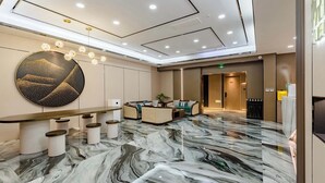 A modern lobby with a marble floor, a reception desk, seating area, and a large wall art piece. - Taian Yuelan Hotel Wanda Plaza Taishan (Tai'an)