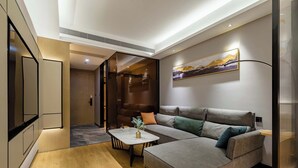 A modern living room with a sectional sofa, a coffee table, and a painting on the wall. - Taian Yuelan Hotel Wanda Plaza Taishan (Tai'an)