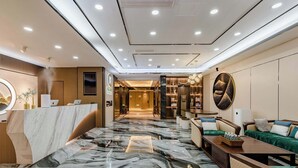 A hotel lobby with a marble floor, a reception desk, seating area, and a wall with decorative items. - Taian Yuelan Hotel Wanda Plaza Taishan (Tai'an)