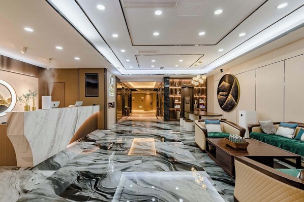A hotel lobby with a marble floor, a reception desk, seating area, and a wall with decorative items. - Taian Yuelan Hotel Wanda Plaza Taishan (Tai'an)