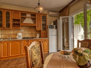 Eine Küche mit Holzausstattung, einer Mikrowelle, einem Kühlschrank und einem Essbereich mit Tisch für zwei Personen.