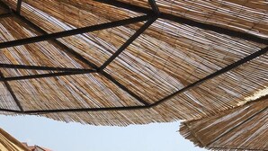 A beachside seating area with a swing set, a slide, and a table under a thatched umbrella. - Bella Casa Srima Comfort by Interhome (Vodice)