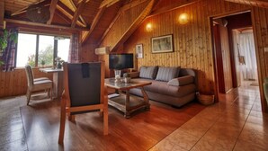Un interior de madera acogedor con techo alto, un sofá, una mesa y un televisor.